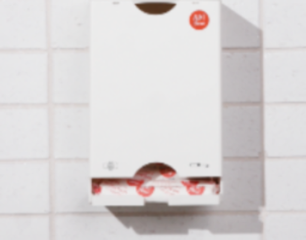 Tissue box mounted on a tiled wall with a visible brand logo.